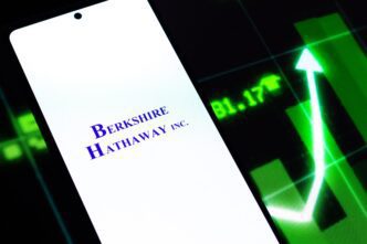 Phone screen displaying the Berkshire Hathaway Inc. logo next to a green financial chart with a sharp upward arrow.