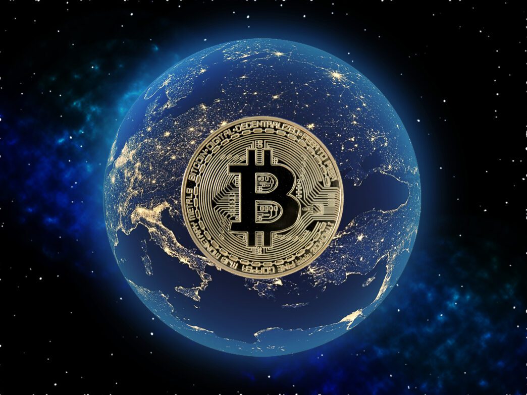 Large gold Bitcoin coin overlaid on the Earth, symbolizing global digital money.