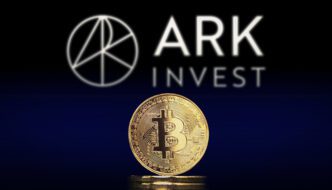 Gold Bitcoin coin in foreground with the blurred ARK Invest logo visible in the background.