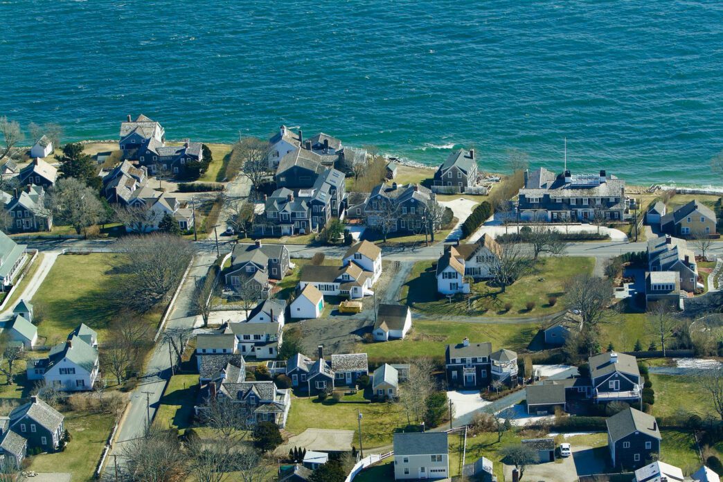Aerial view of a seaside neighborhood in Maine, USA, with densely packed houses near the turquoise water.
