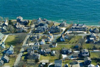Aerial view of a seaside neighborhood in Maine, USA, with densely packed houses near the turquoise water.