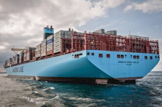 The large Maersk Mc-Kinney Møller container ship sailing on the water under a cloudy sky.
