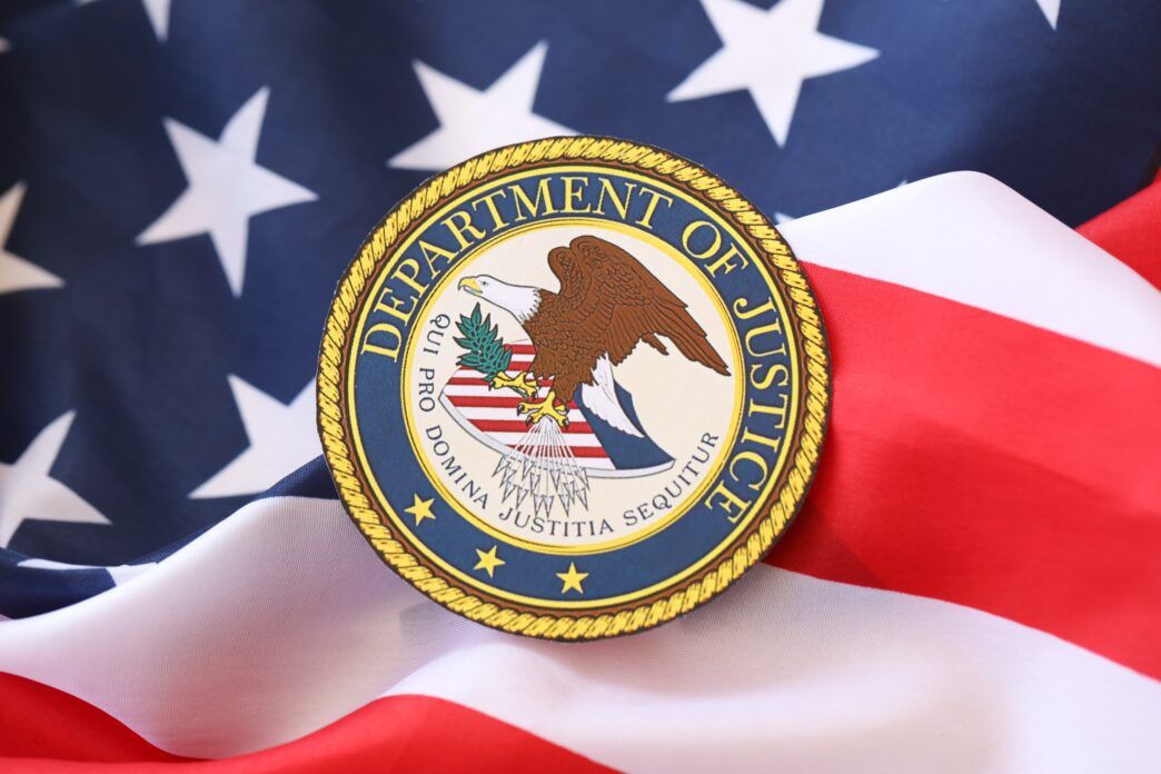 The seal of the U.S. Department of Justice placed on the folds of a waving American flag.