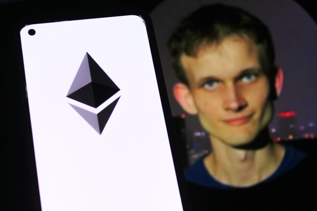 Smartphone displaying the Ethereum logo next to a blurred image of co-founder Vitalik Buterin.