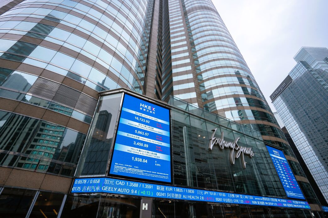 Low-angle view of the Hong Kong Stock Exchange building with a large blue digital display.
