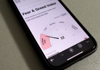 Smartphone displaying the Fear & Greed Index reading 22, indicating "Extreme Fear" in the market.