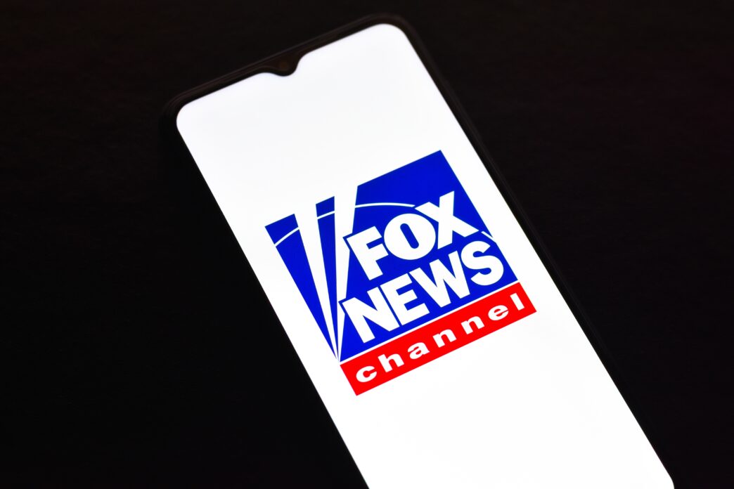Close-up of a smartphone screen displaying the distinctive blue, white, and red Fox News Channel logo.