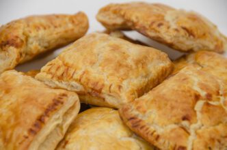 A close-up view of a pile of golden-brown, square guava puff pastries.