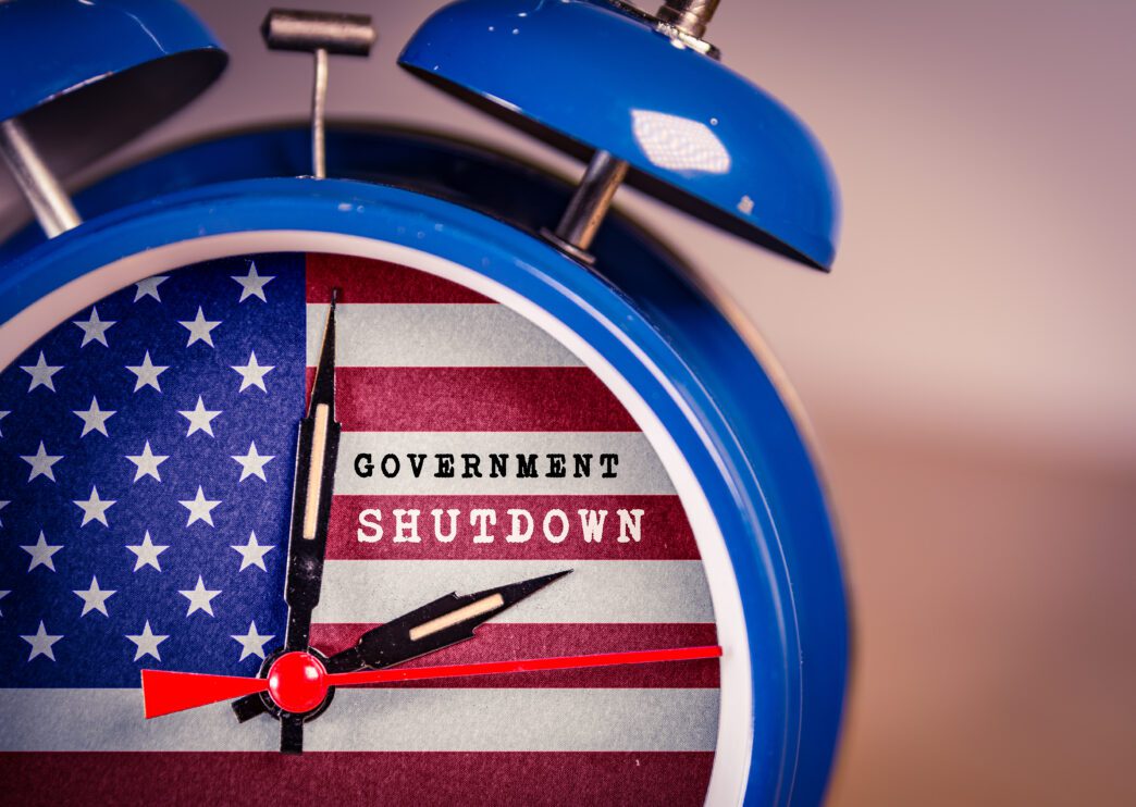 Alarm clock with the US flag face displaying "Government Shutdown" text.