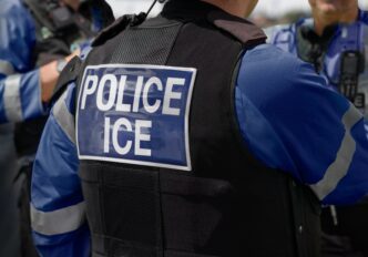 Close-up rear view of an Immigration and Customs Enforcement (ICE) officer's uniform and vest.