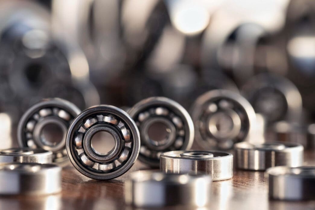 Close-up, shallow depth-of-field shot of several small, shiny ball bearings scattered on a wooden surface.