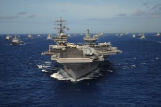 The USS Ronald Reagan leads a massive formation of international warships on the ocean.