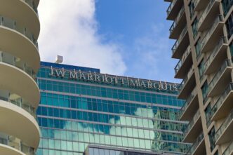 Exterior sign for the JW Marriott Marquis hotel visible between two high-rise buildings in Miami.