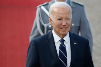 Close-up of Joe Biden smiling while being received with military honors in Berlin.