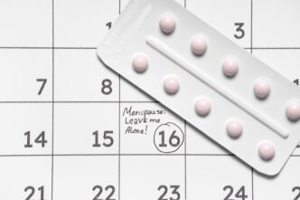 A blister pack of pink pills resting on a calendar with "Menopause: Leave me Alone!" written on day 15.