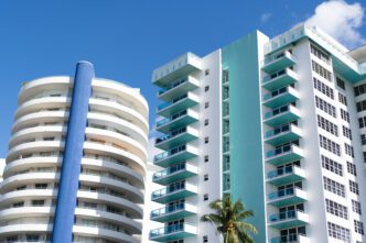 Modern, colorful condominium buildings with curved balconies against a bright blue sky in Miami Beach.