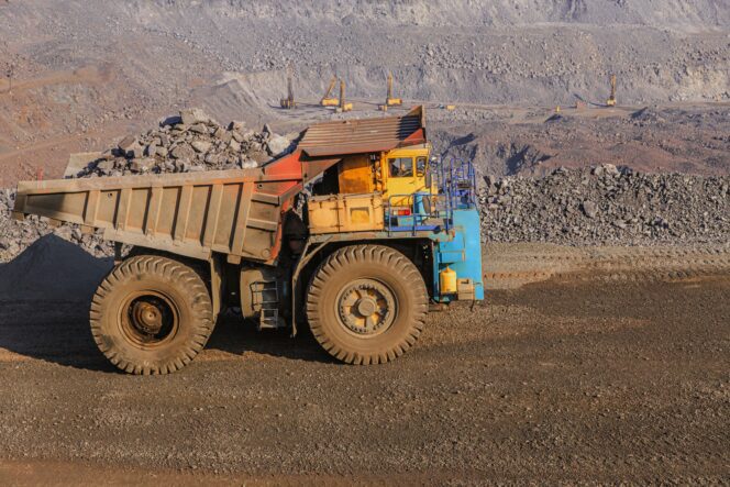 Large, old mining haul truck loaded with rocks in a quarry extraction site.