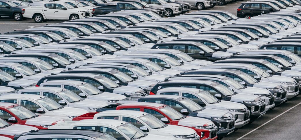 Dense, ordered rows of brand-new vehicles waiting in a large factory loading yard.