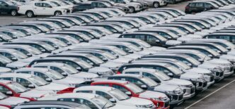 Dense, ordered rows of brand-new vehicles waiting in a large factory loading yard.