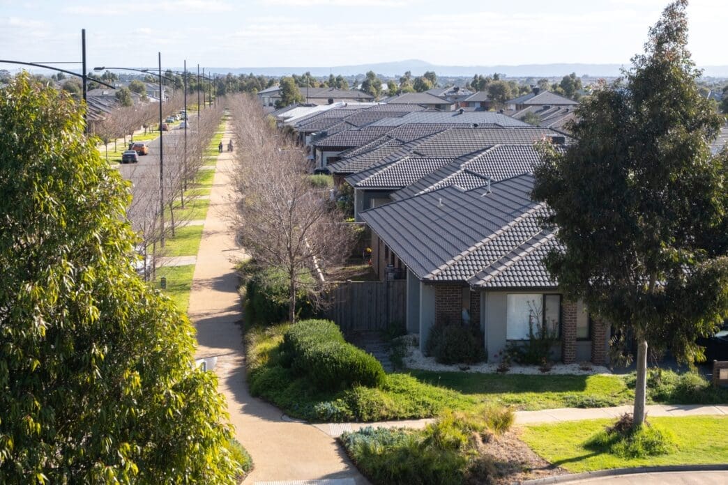 Aerial view of a long, straight street lined with modern, identical-roofed suburban homes in Melbourne.