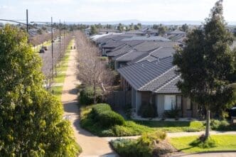 Aerial view of a long, straight street lined with modern, identical-roofed suburban homes in Melbourne.