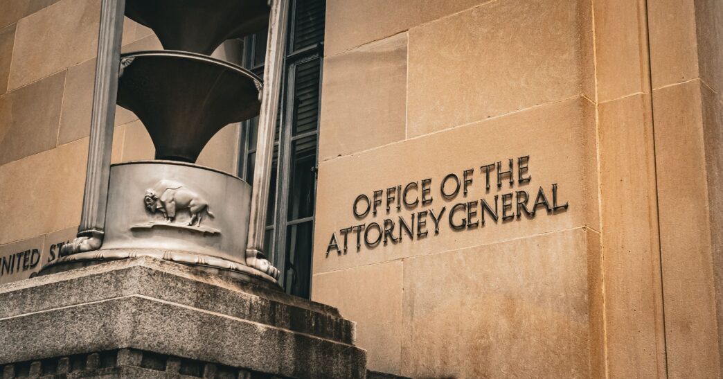 Close-up of the sandstone exterior of the U.S. Justice Department building with the Attorney General sign.