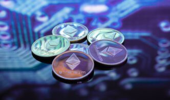 A cluster of physical Ethereum cryptocurrency coins on a blurred blue circuit board background.
