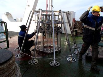 Science team preparing a multi-core sampler on a ship deck for deepwater research.