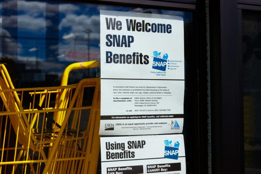 Sign on a retailer's window stating "We Welcome SNAP Benefits" with USDA anti-discrimination and contact information.