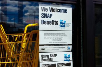 Sign on a retailer's window stating "We Welcome SNAP Benefits" with USDA anti-discrimination and contact information.