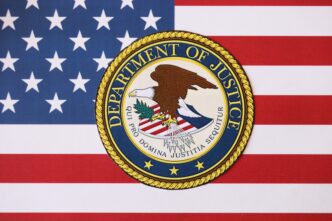 Seal of the US Department of Justice centered over the stripes and stars of the American flag.