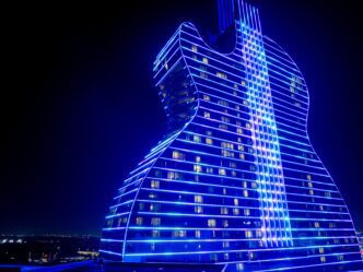 Seminole Hard Rock Guitar Hotel lit up brightly with neon blue lights at night.