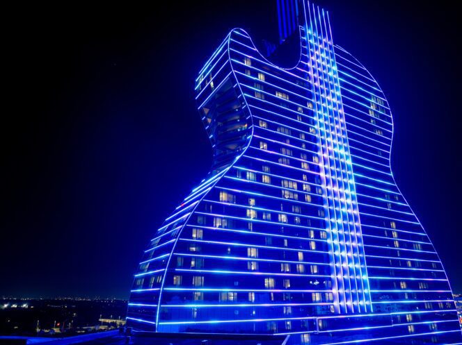 Seminole Hard Rock Guitar Hotel lit up brightly with neon blue lights at night.