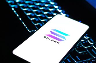 Smartphone screen displaying the Solana cryptocurrency logo over a backlit keyboard.