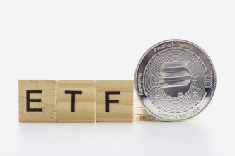 Wooden letter tiles spelling "ETF" next to a silver Solana cryptocurrency coin.
