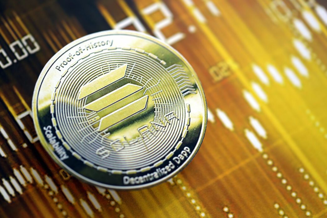 Close-up of a gold Solana coin with "Proof-of-History" inscription on a dark gold digital chart background.