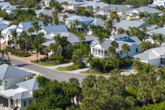 Aerial view of a premium housing development with white houses and dense palm trees in Florida.
