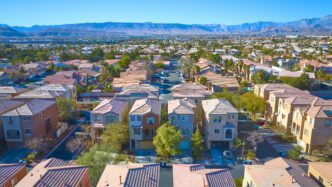 Aerial view of a dense, uniformly designed suburban neighborhood in Las Vegas, backed by mountains.