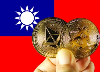 Hand holding a gold Bitcoin and an Ethereum coin against the background of the Taiwanese flag.