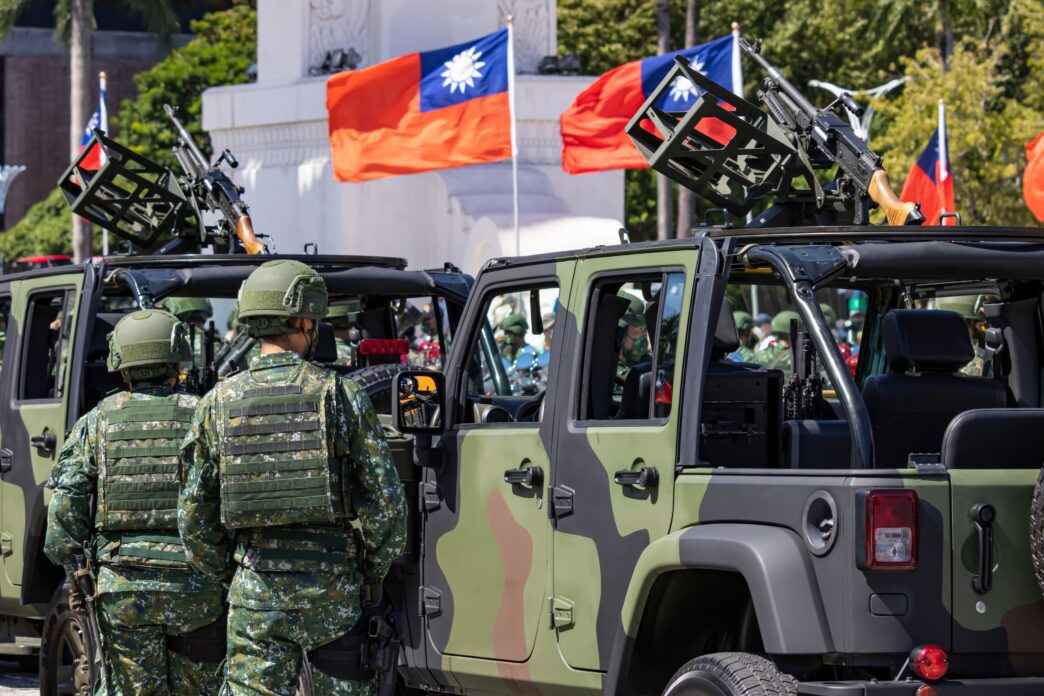Taiwanese soldiers and camouflaged military vehicles with mounted guns during a National Day parade.