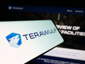 TeraWulf Inc. logo and name displayed on a mobile phone screen in front of the company website.