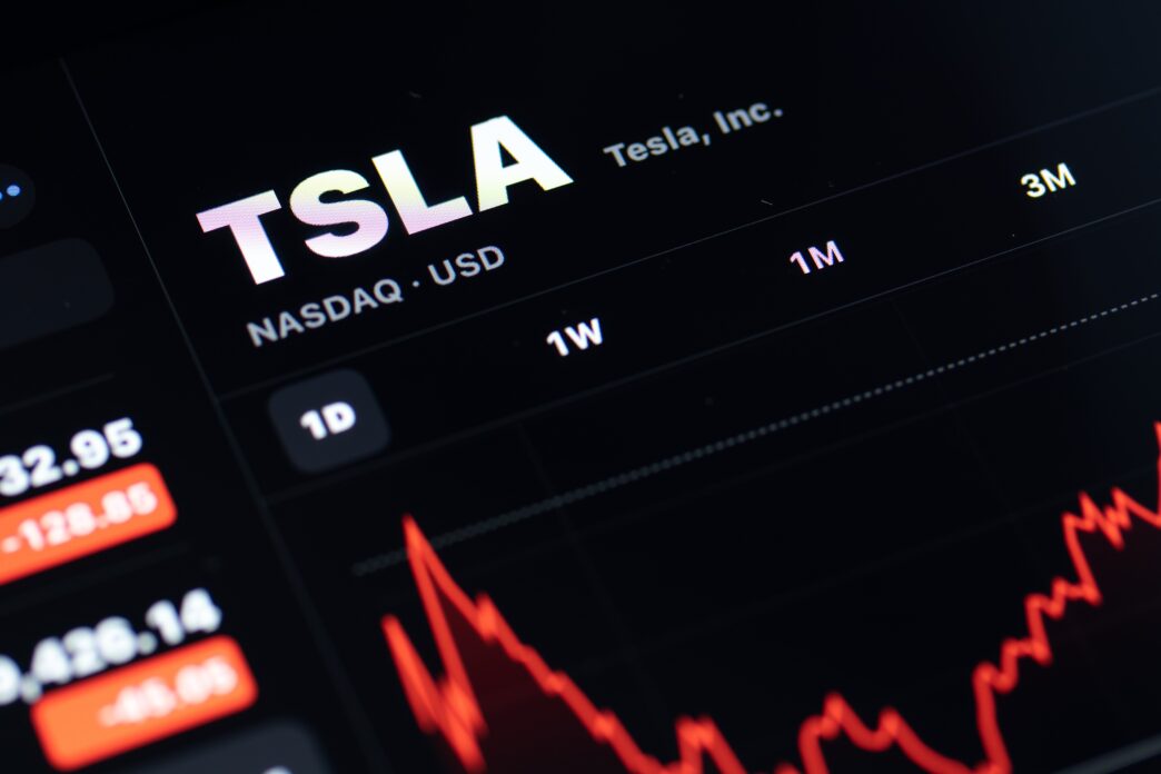 Close-up of a digital screen showing the TSLA stock chart with a pronounced red (negative) trend.