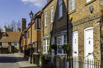 Row of traditional brick terraced houses in a UK suburb on a sunny day.