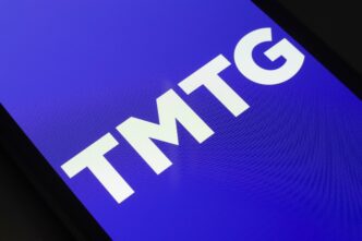 Close-up of the white "TMTG" logo on a vibrant blue background displayed on a smartphone screen.