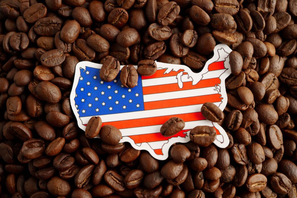 Map outline of the USA with the American flag design, placed on a pile of roasted coffee beans.