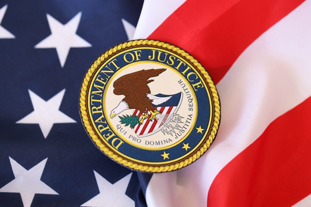 The seal of the US Department of Justice placed on the folds of a fabric American flag.