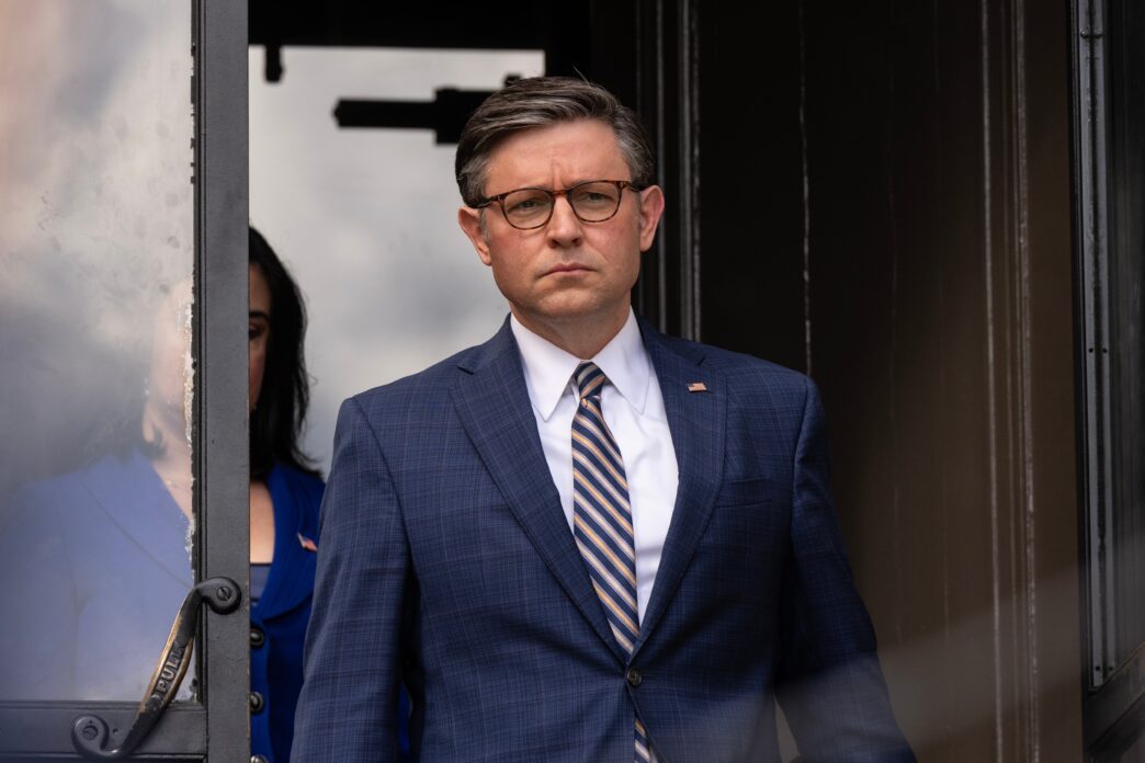 Close-up of US House Speaker Mike Johnson standing in a doorway, wearing glasses and a suit.