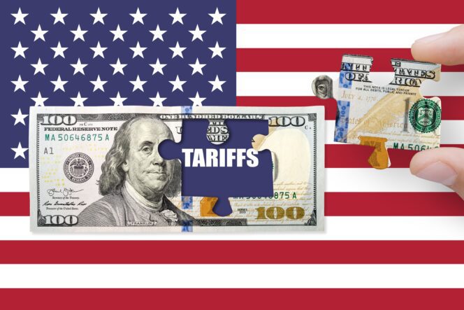 Puzzle piece with the word "TARIFFS" being removed from a $100 bill overlaid on the US flag.