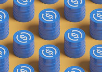 Seamless pattern of stacked blue USDC stablecoin tokens on a yellow background.