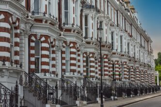 Row of historic London townhouses with red brick and white stucco facades and ornate iron railings.